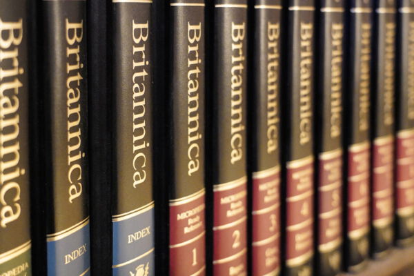 Eine Reihe von Bänden der Encyclopedia Britannica in einem Regal aus dunklem Holz